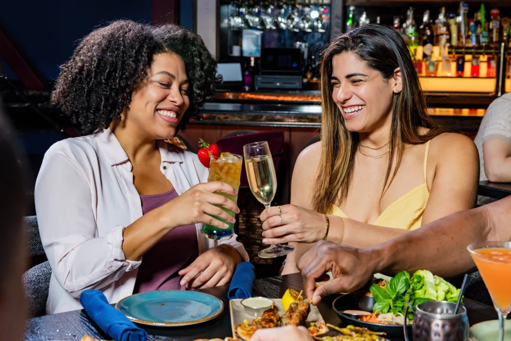 Two women smiling and clinking their drinks