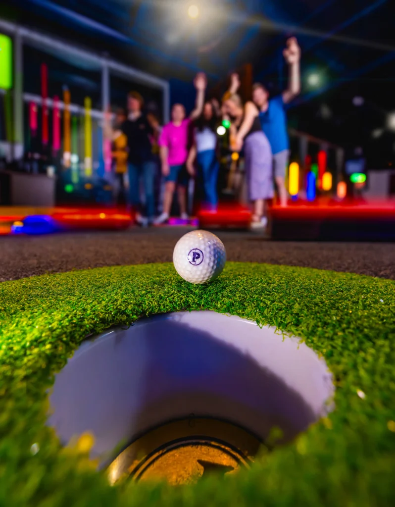 A Puttshack golf ball about to go into a hole