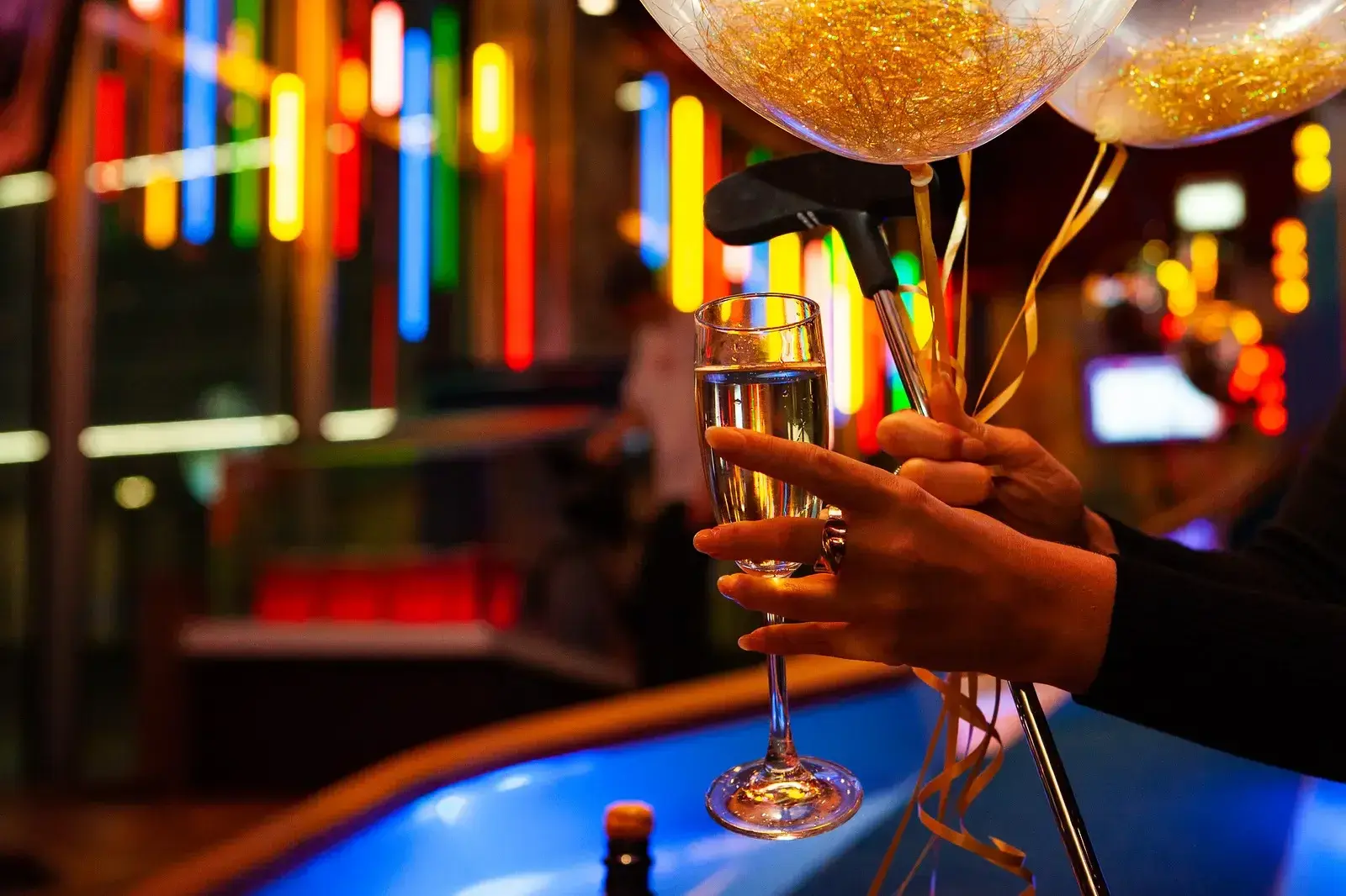 someone holding a glass of bubbly, balloons and a putt