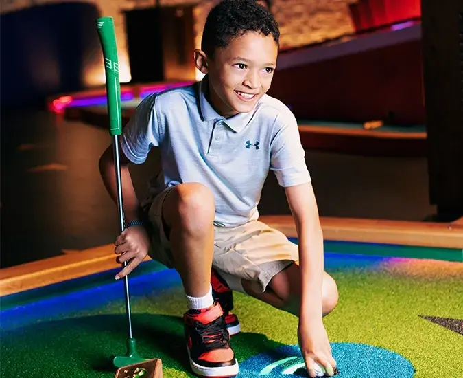 Little Boy knelt down placing a ball down