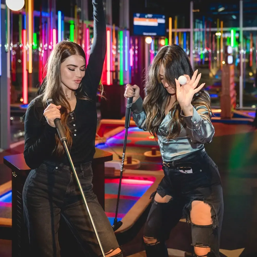 two girls celebrating holding putts and a golf ball