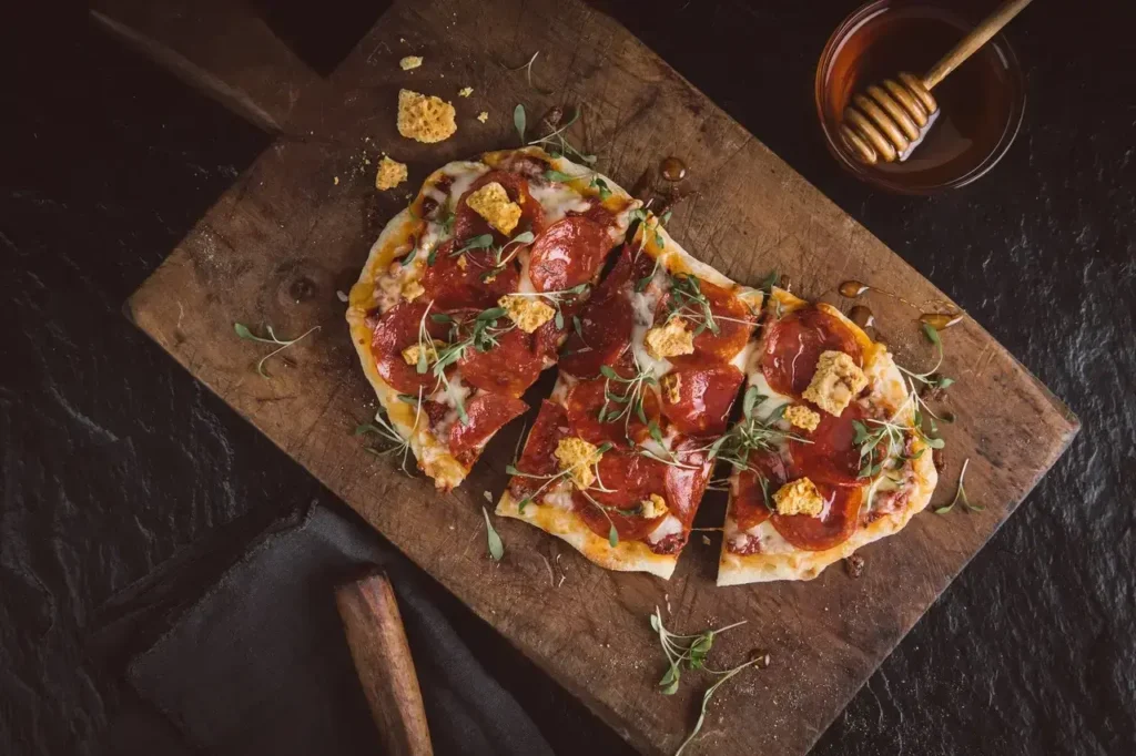 A meat flatbread with a honey ladle