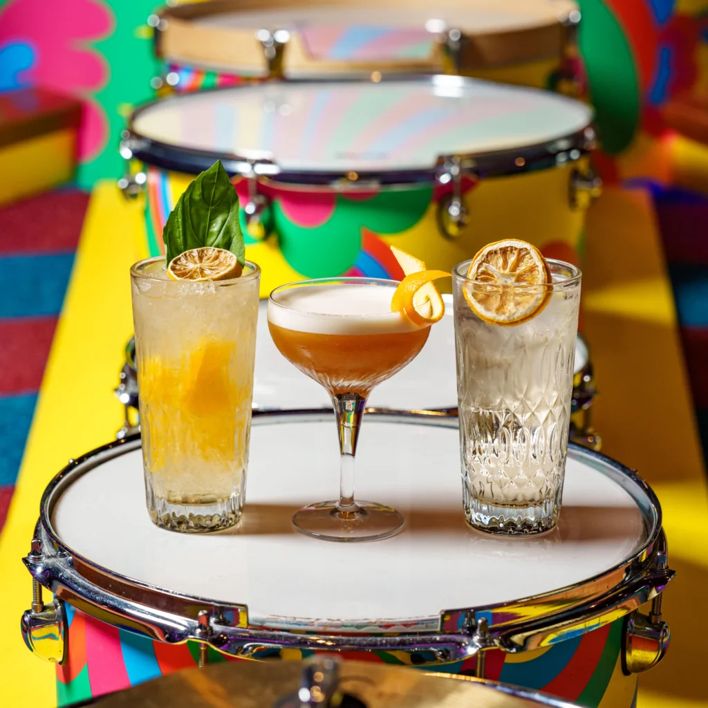 three specialty cocktails on a snare drum