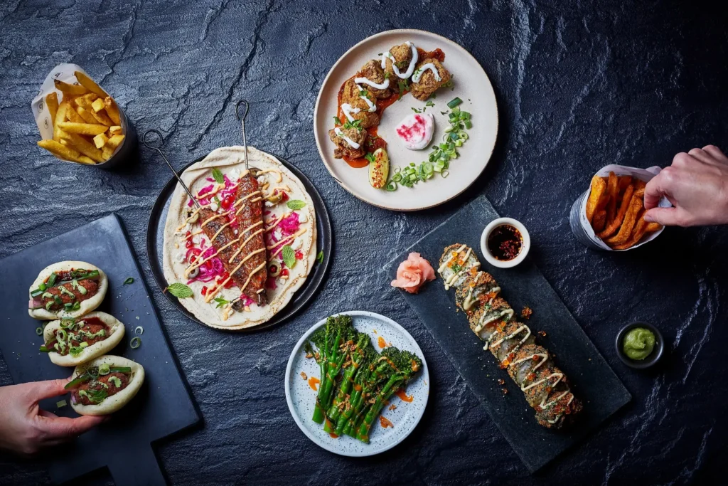 Food on display: bao buns, broccolini, kabobs, sushi, and fries