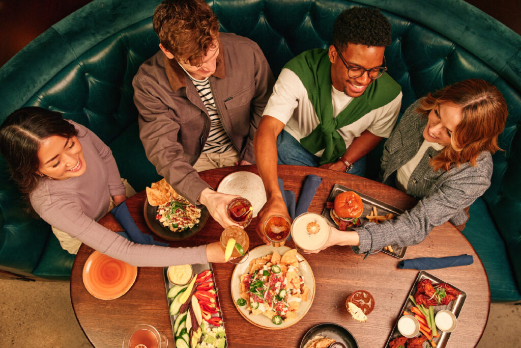 Group of guests eating and cheersing at a table in Puttshack.