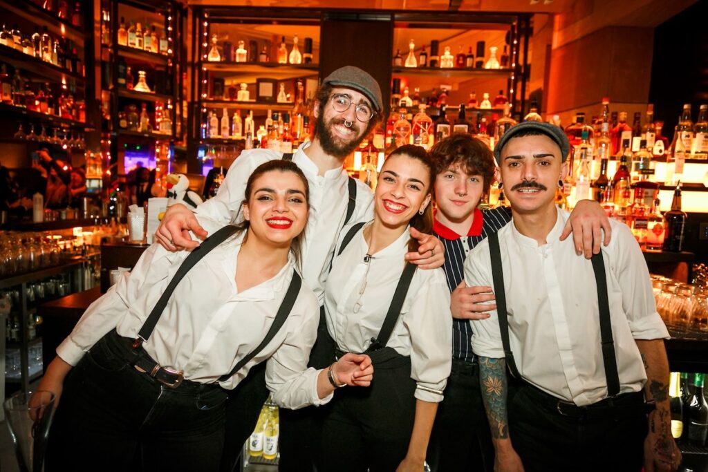 Five Puttshack colleagues smiling and posing behind the cocktail bar