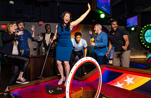 Group of people gathered around an indoor mini golf course